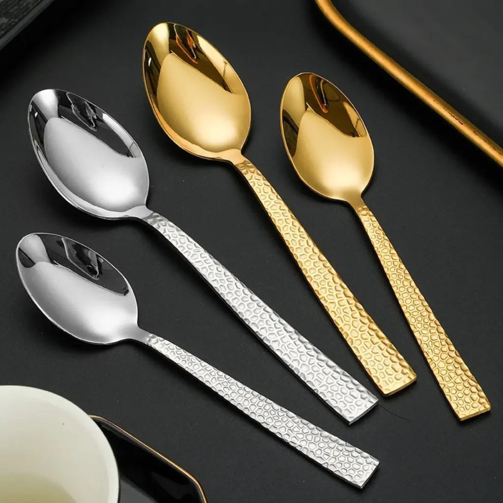 Conjunto de talheres dourado e prata com textura martelada, em composição elegante com tecido preto – estilo contemporâneo com toque de requinte.